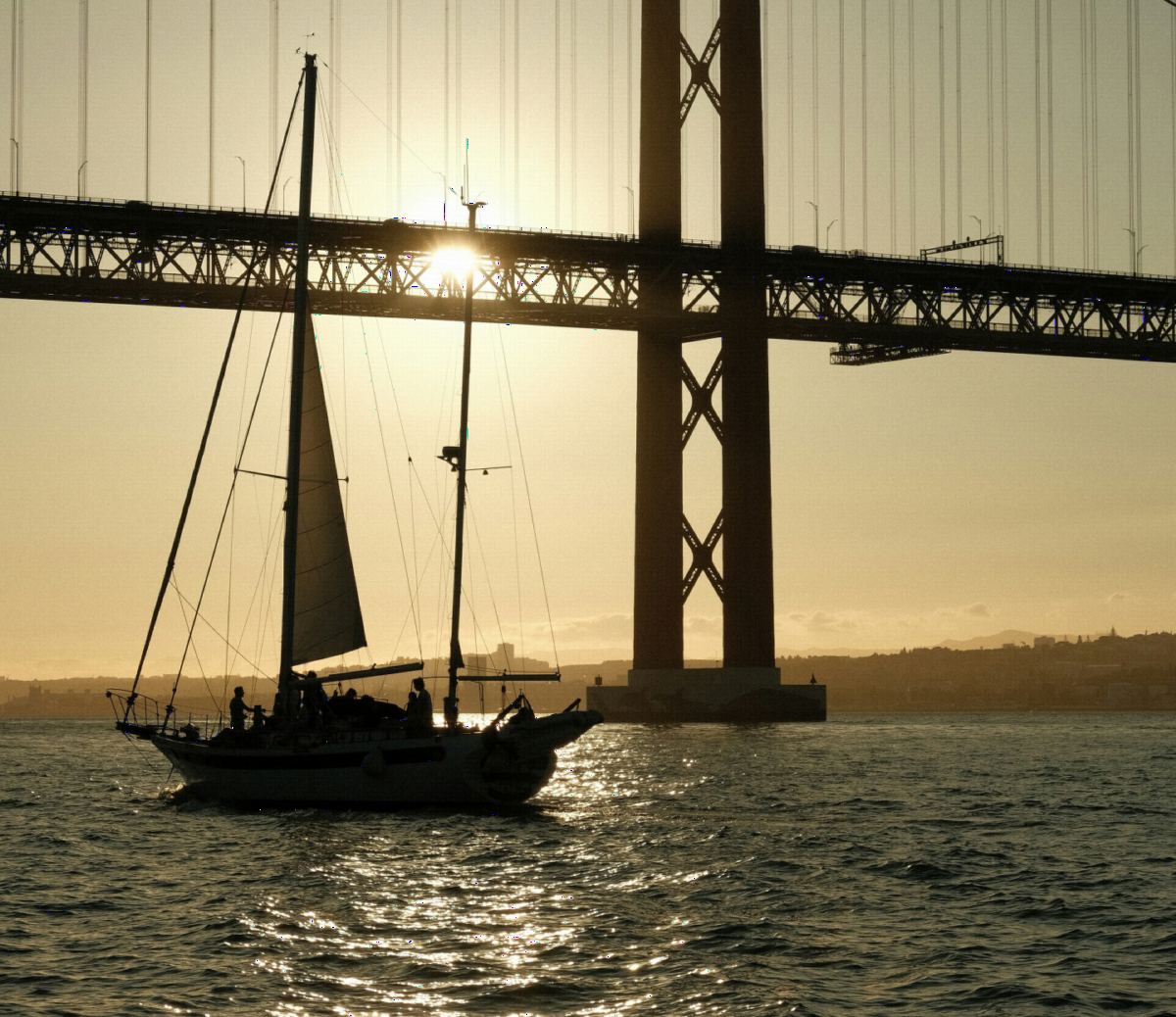 A sailboat under the 25 de Abril Bridge